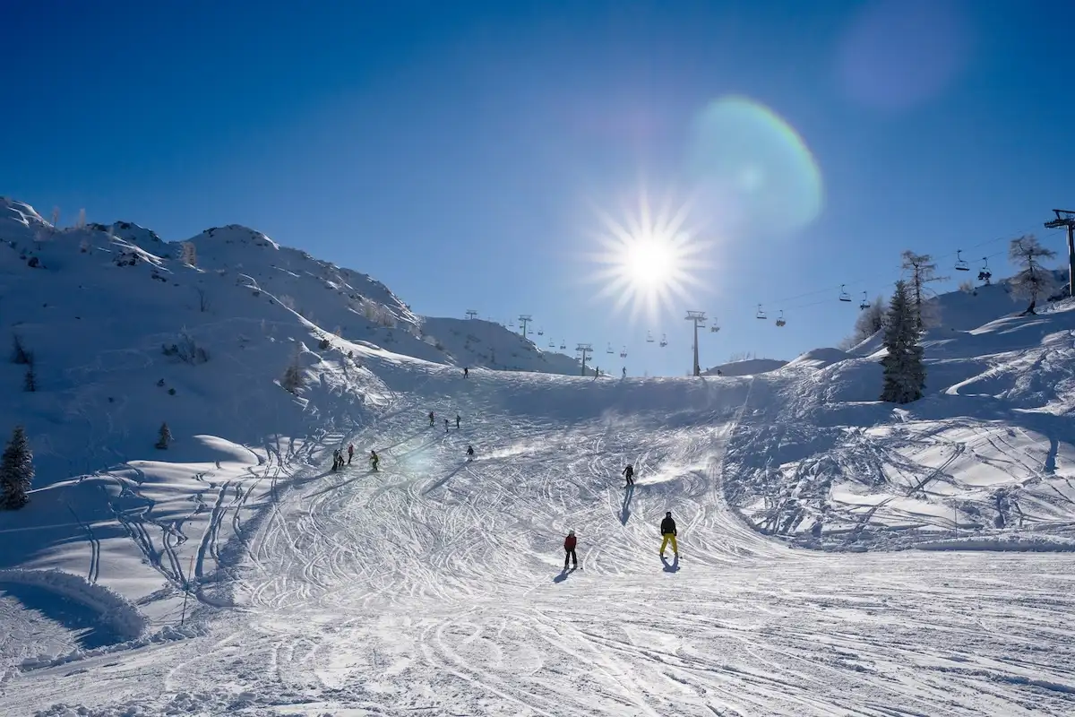 Skijaši na sunčanoj snježnoj stazi u planinama